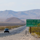 A car drives down a highway through the desert